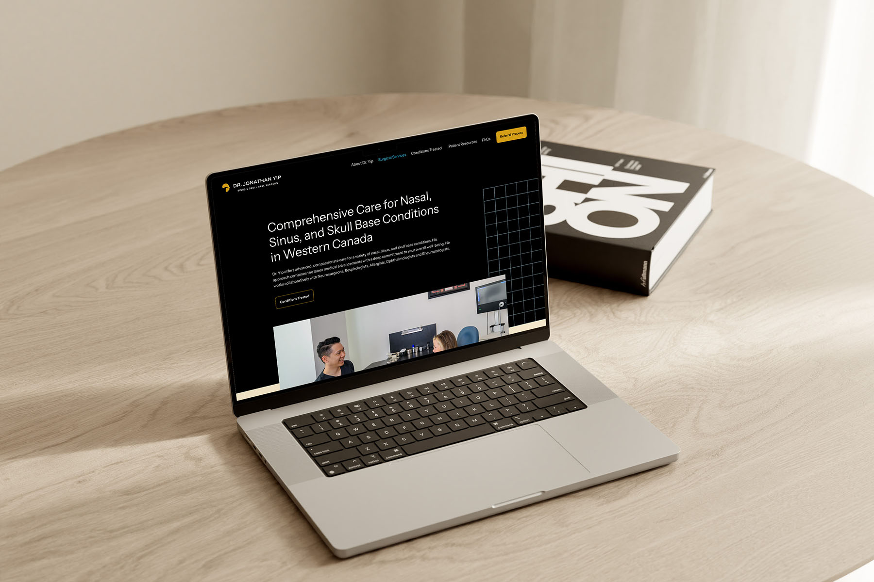 A laptop displaying Dr. Jonathan Yip’s website on a light wood table, emphasizing a clean and professional web design for medical services.