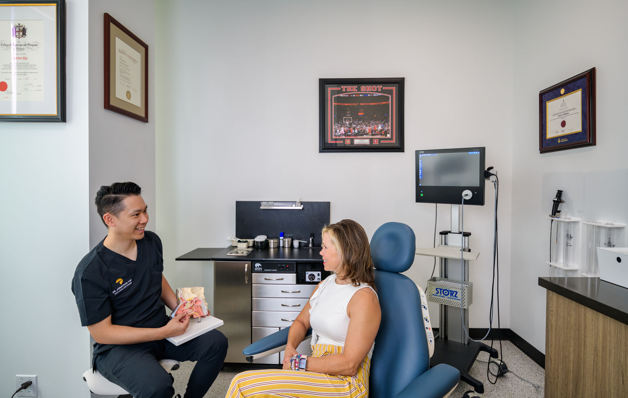 Dr. Jonathan Yip consulting with a patient in a professional medical office, discussing treatment options with anatomical models.