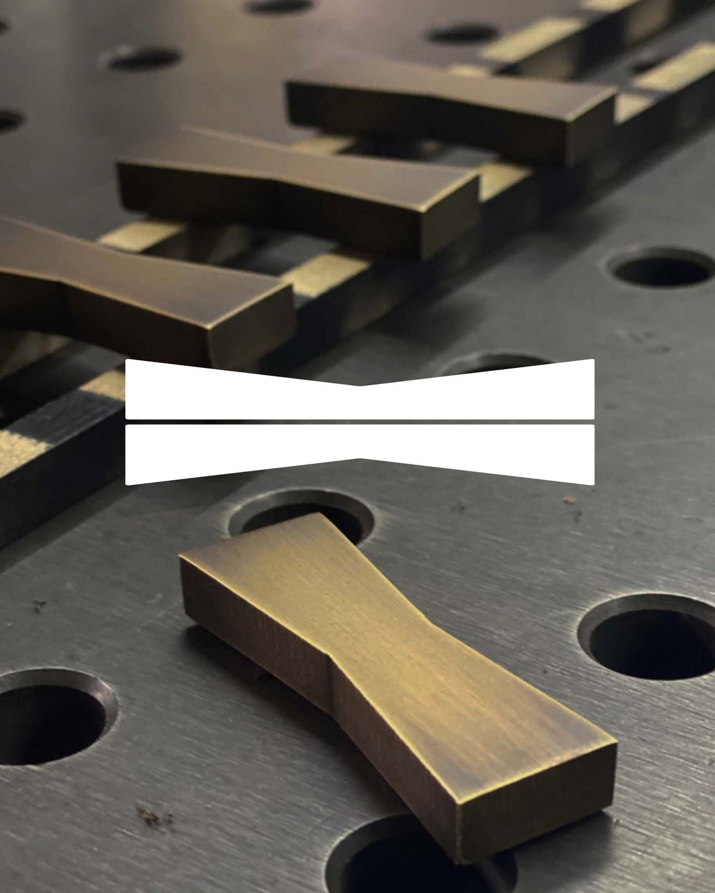 Close-up of brass bowtie inlays used in Withers Studio’s custom furniture designs, featuring their signature logo shape, showcasing precision craftsmanship and branding integration.