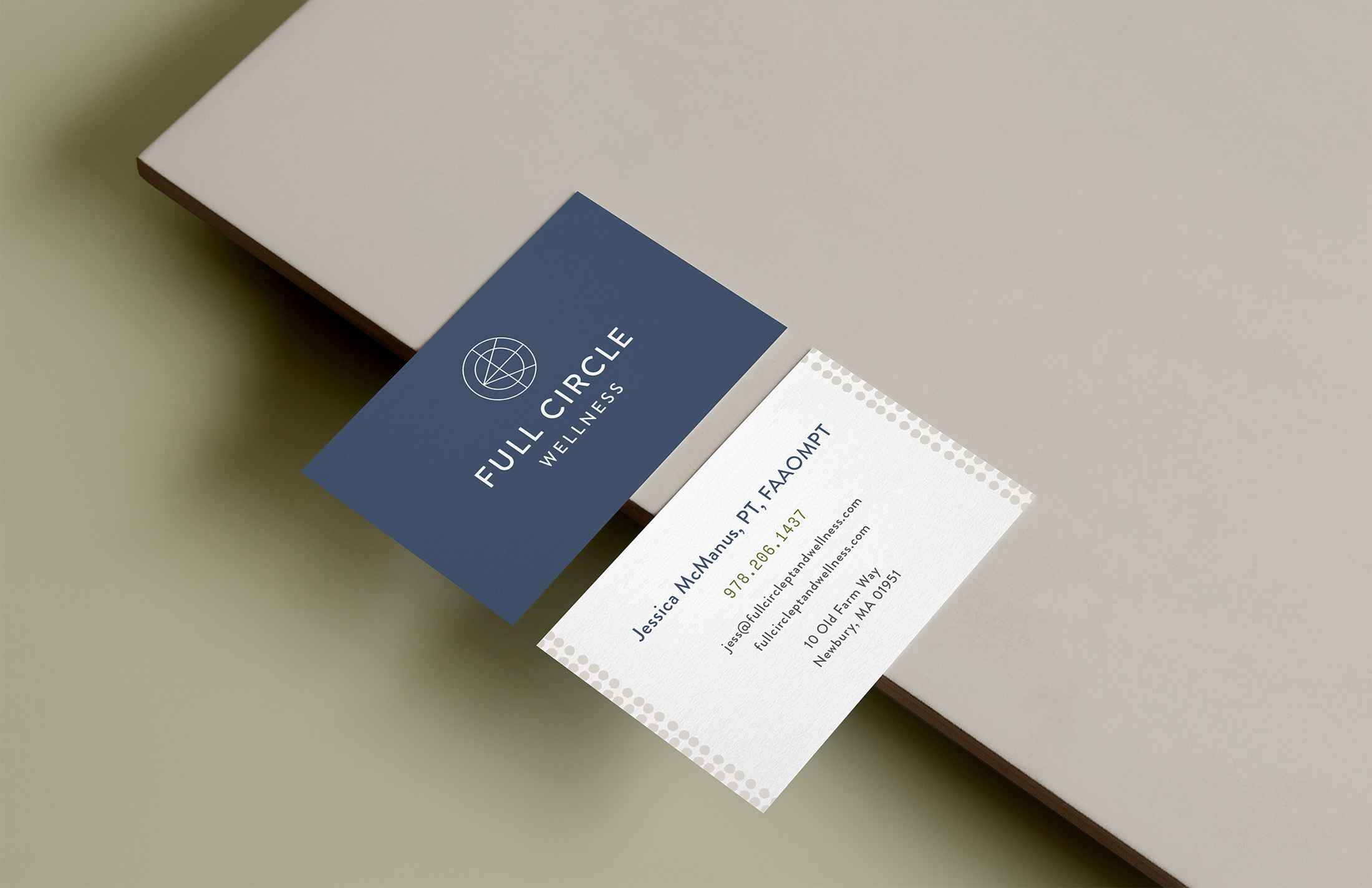 Two business cards for Full Circle Wellness displayed on a minimalistic beige and green background, featuring contact details and the geometric logo.