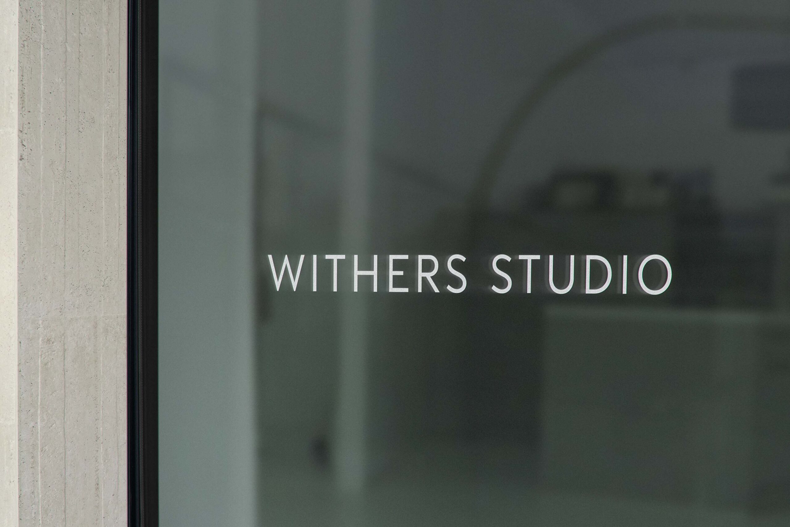 Withers Studio logo etched on a sleek glass window, emphasizing minimalist branding and refined design.