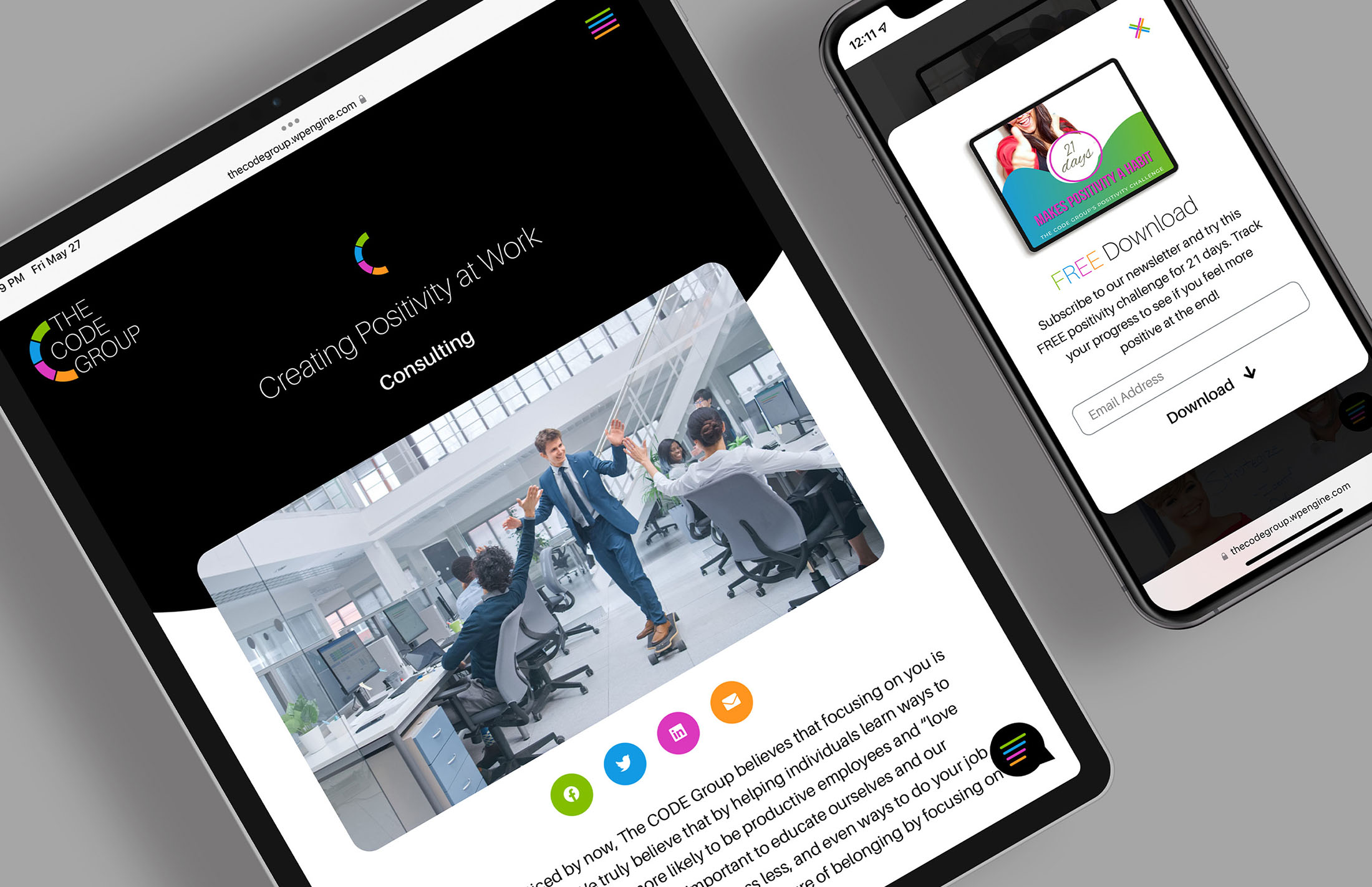 A tablet and smartphone displaying The CODE Group’s consulting services page, highlighting a dynamic office scene and a “Free Download” offer for their positivity challenge.