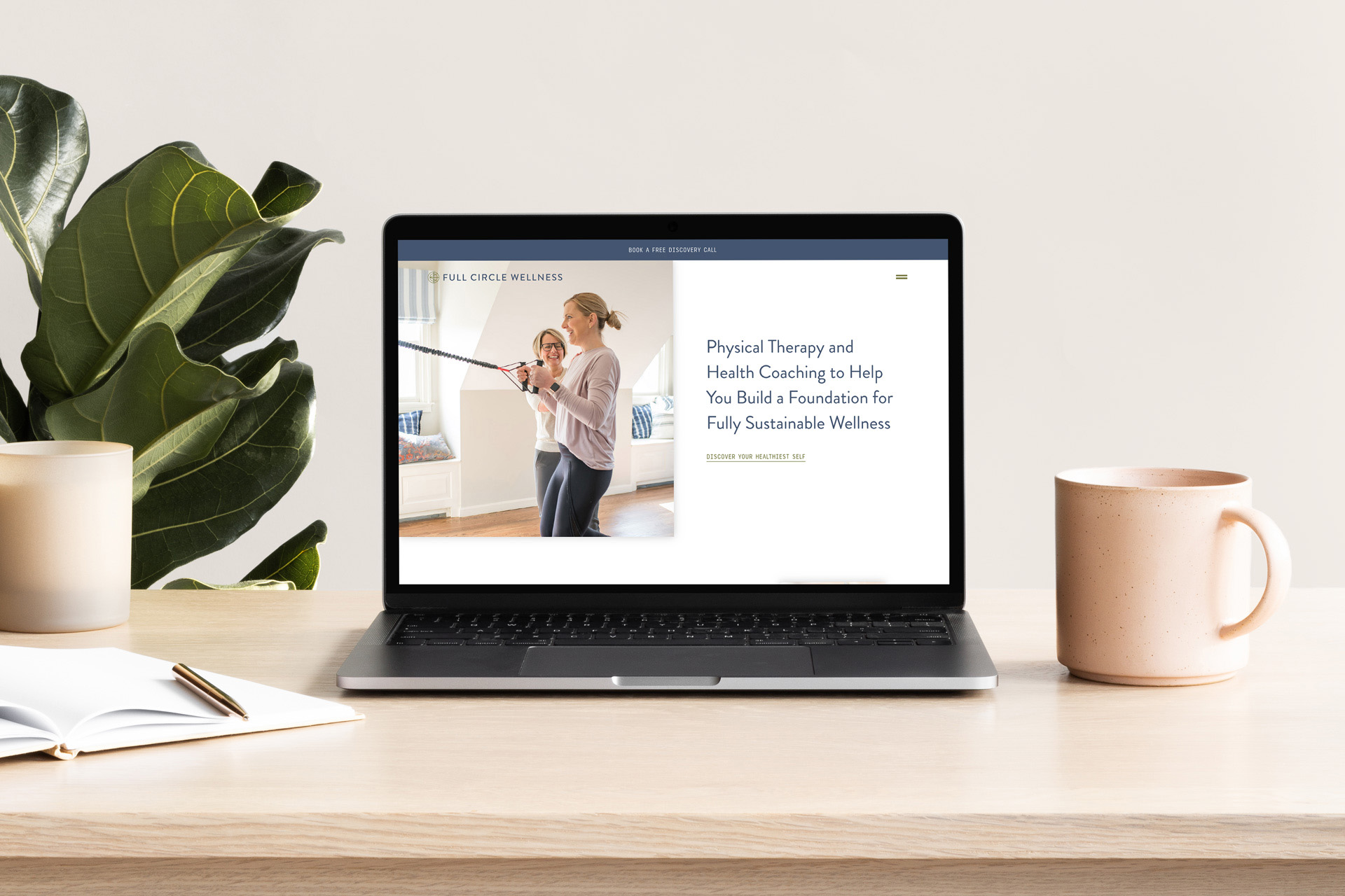 A laptop on a wooden desk displaying the Full Circle Wellness homepage with a focus on physical therapy and health coaching.