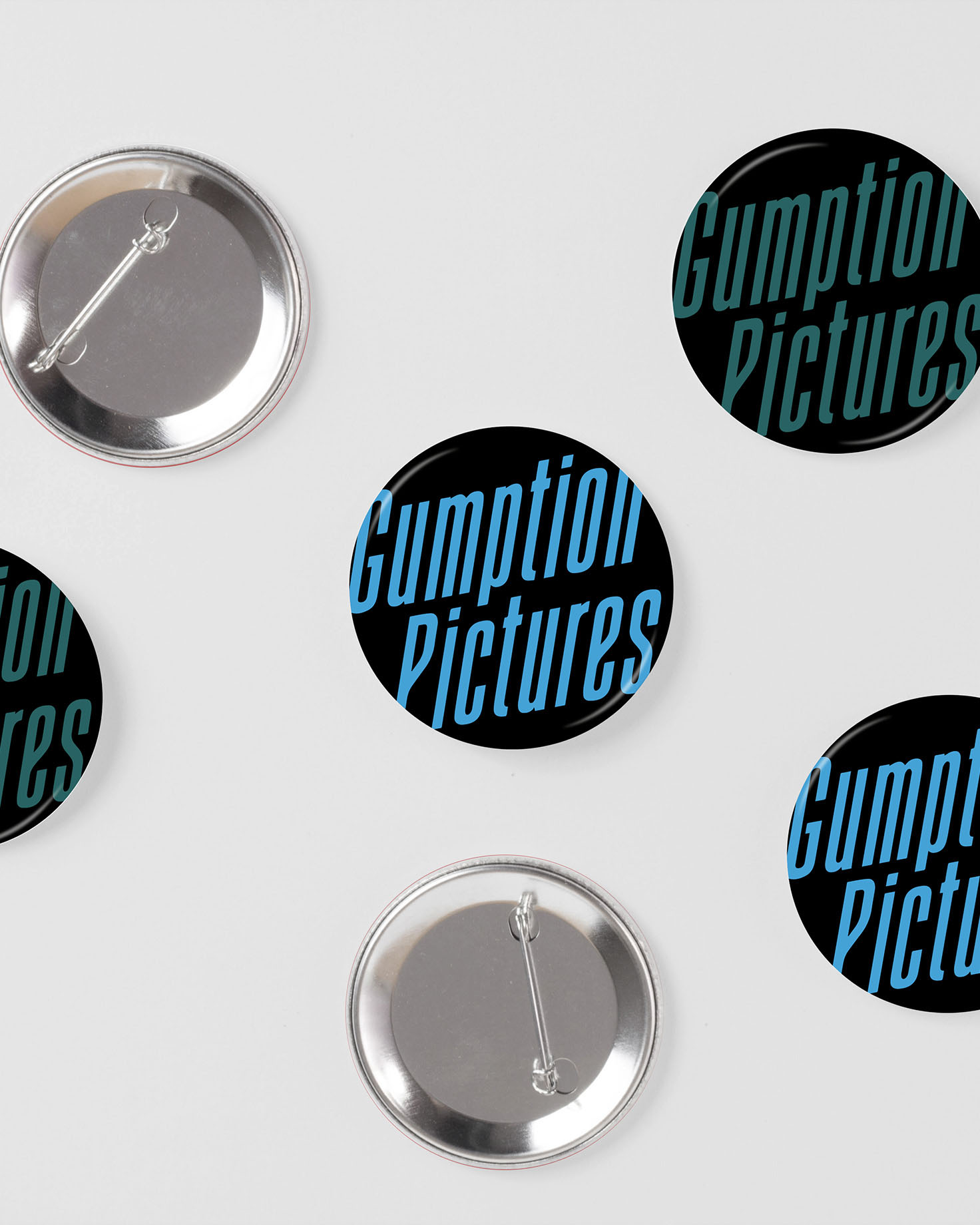 Custom sticker and pin designs for Gumption Pictures featuring bold typography and branded patterns, created for marketing and promotional use.