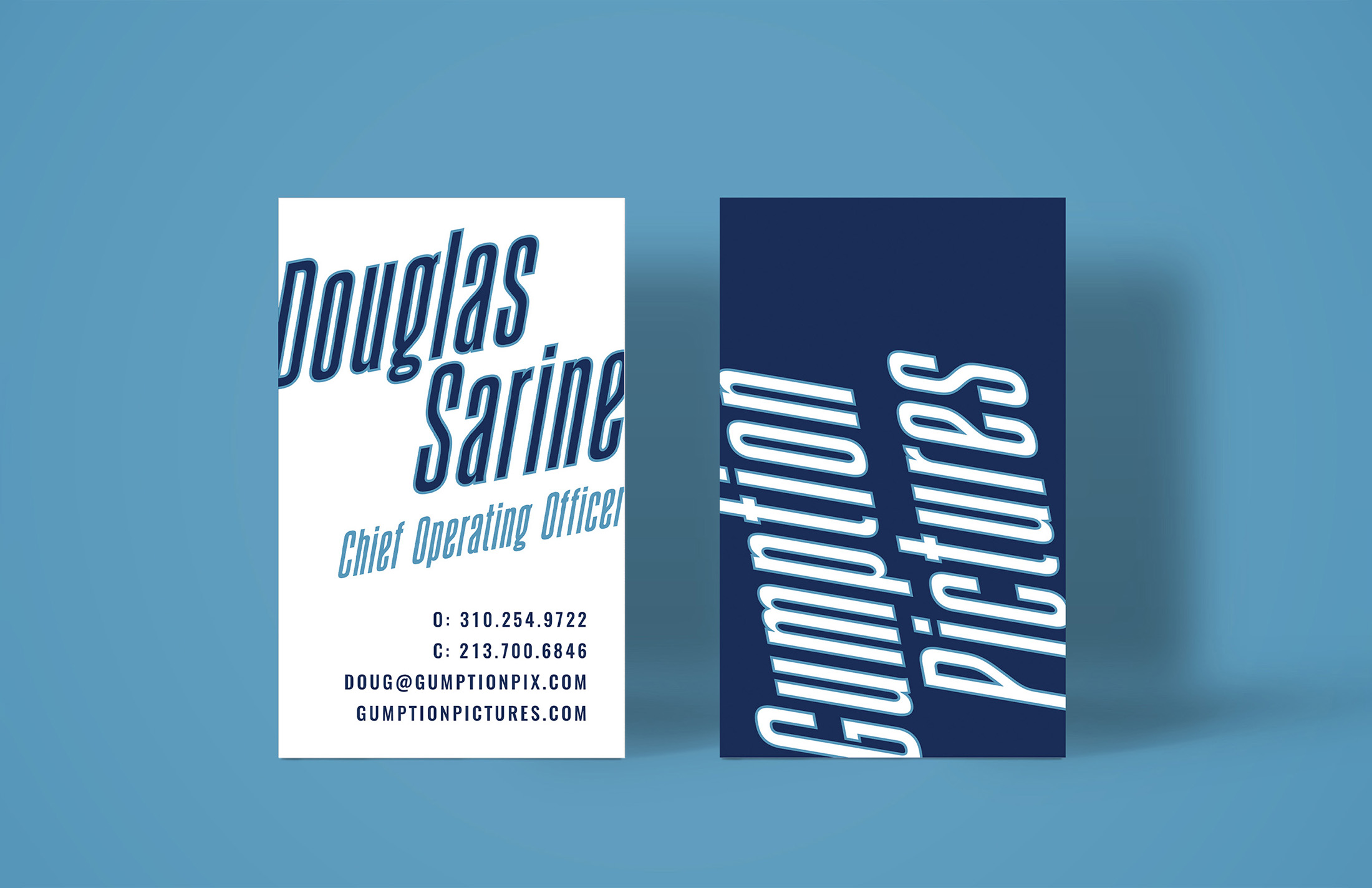 Business card design for Gumption Pictures featuring bold typography with the name Douglas Sarine and contact information on one side and the logo on a navy blue background on the other, showcasing a cohesive brand identity.