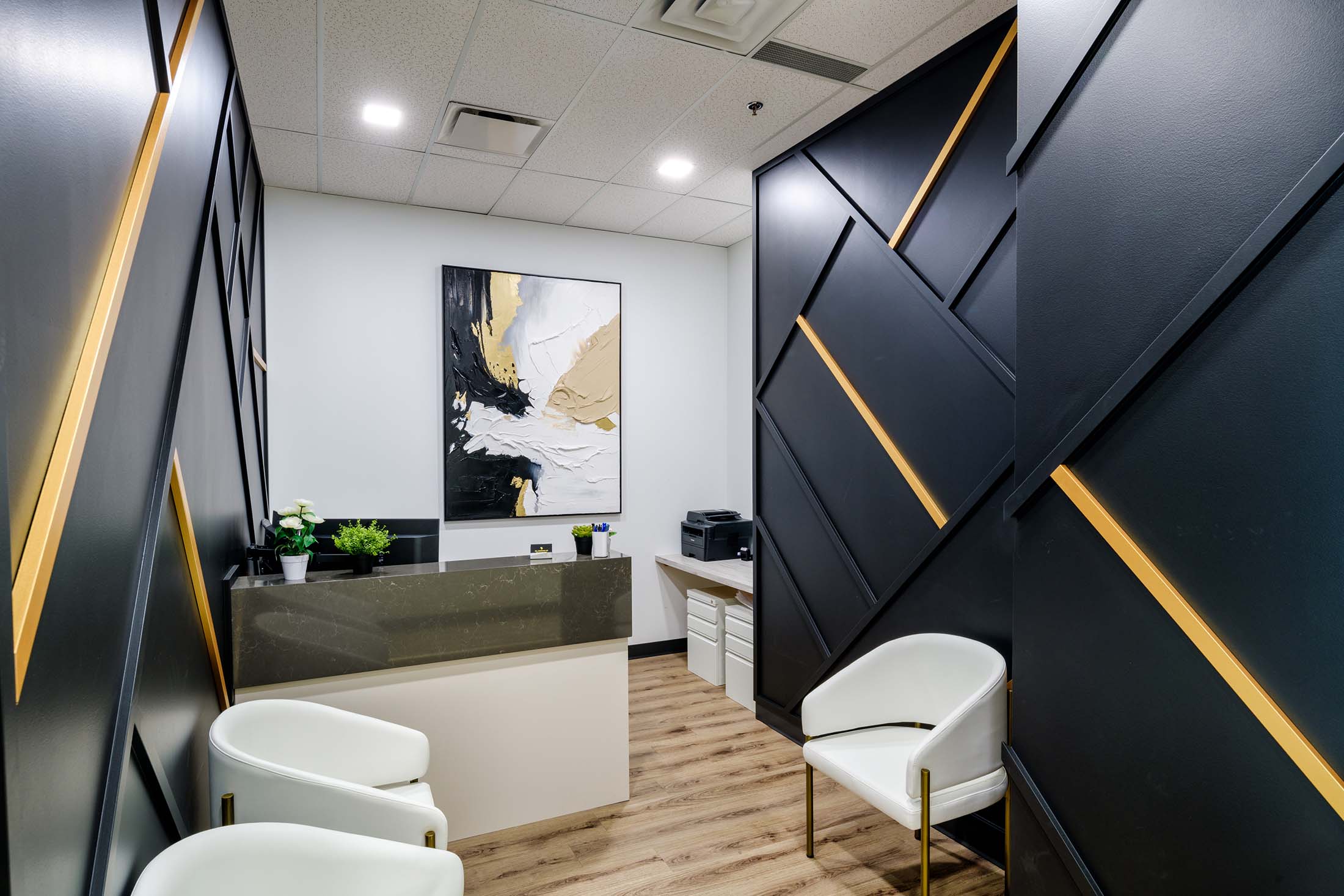 Modern medical office reception area with a black and gold accent wall, white chairs, and a minimalist design for a welcoming atmosphere.