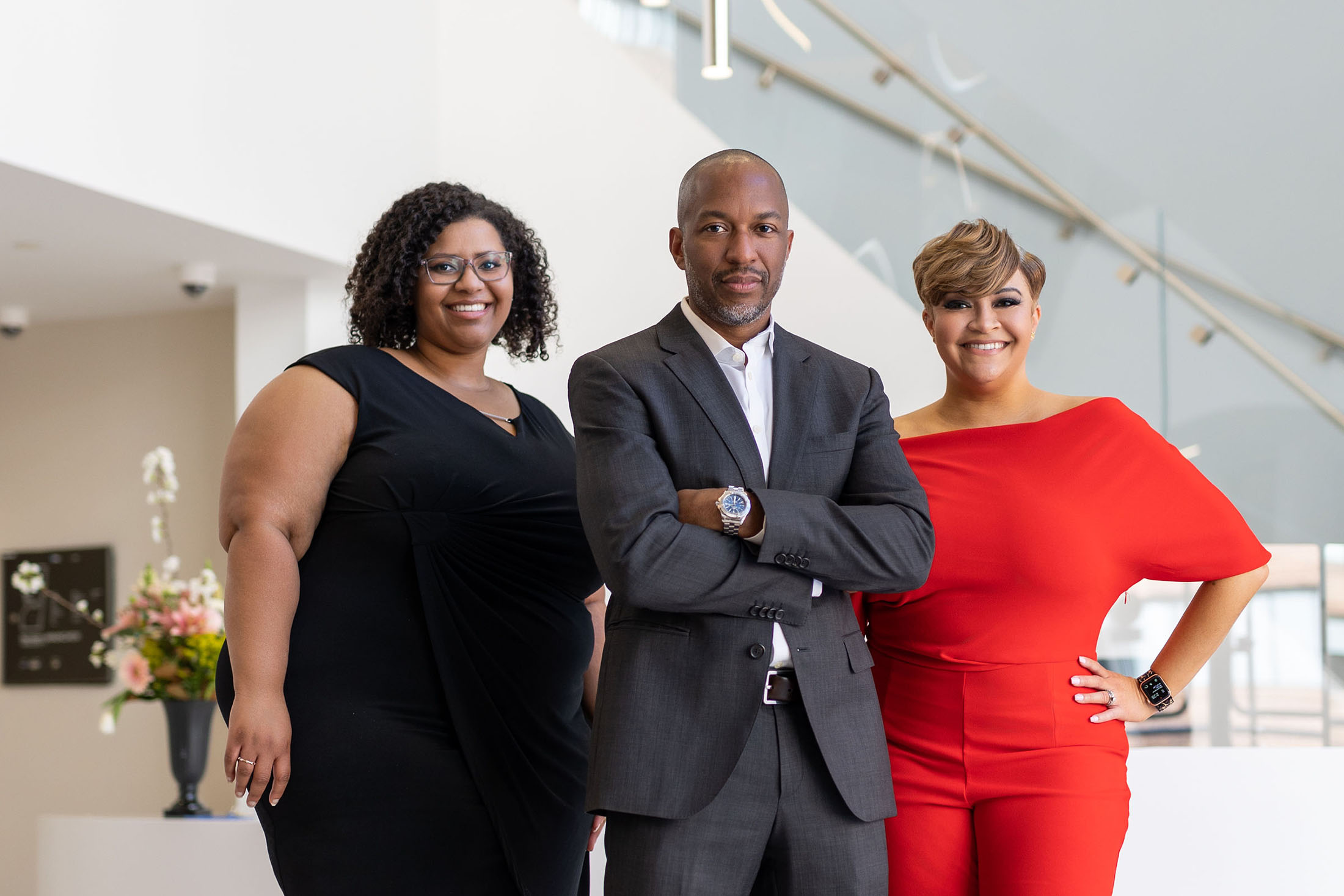 The CODE Group team standing confidently in a modern office environment, featuring a diverse and professional group of three individuals.