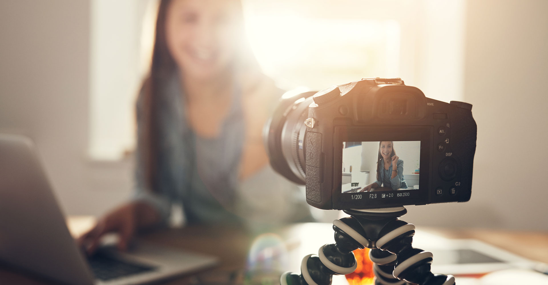 Close-up of a camera recording a woman in a bright workspace, showcasing how blogging and video content can enhance personal branding and online visibility.