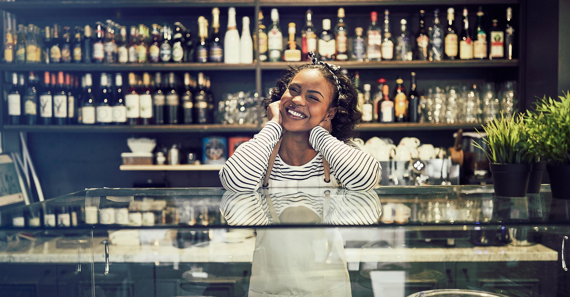 Smiling small business owner standing confidently behind the counter, showcasing personal branding in a visually appealing workspace for website design inspiration.