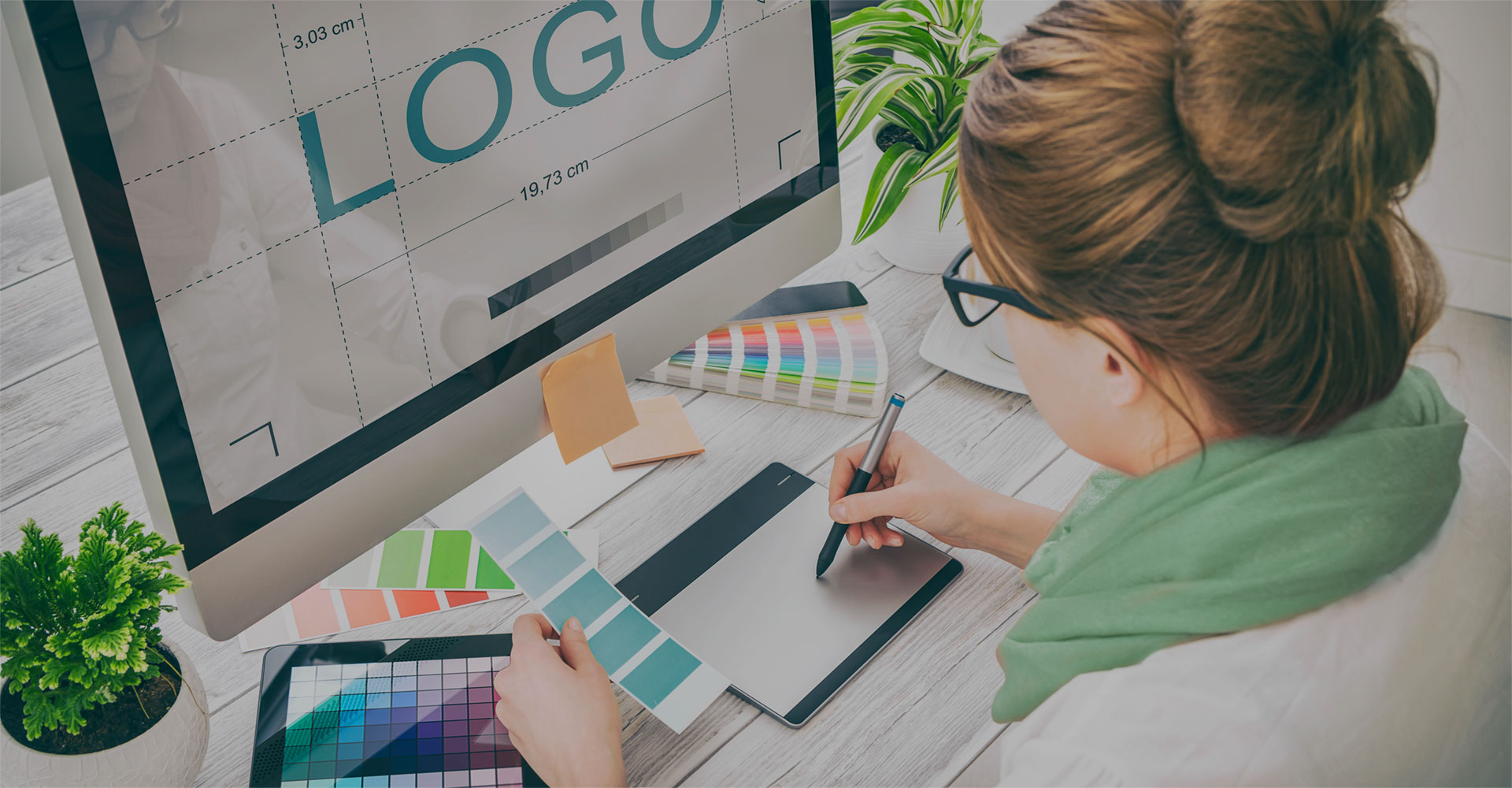 Designer using a tablet and color swatches to create a professional logo, highlighting the challenges and risks of DIY design in branding and visual identity.