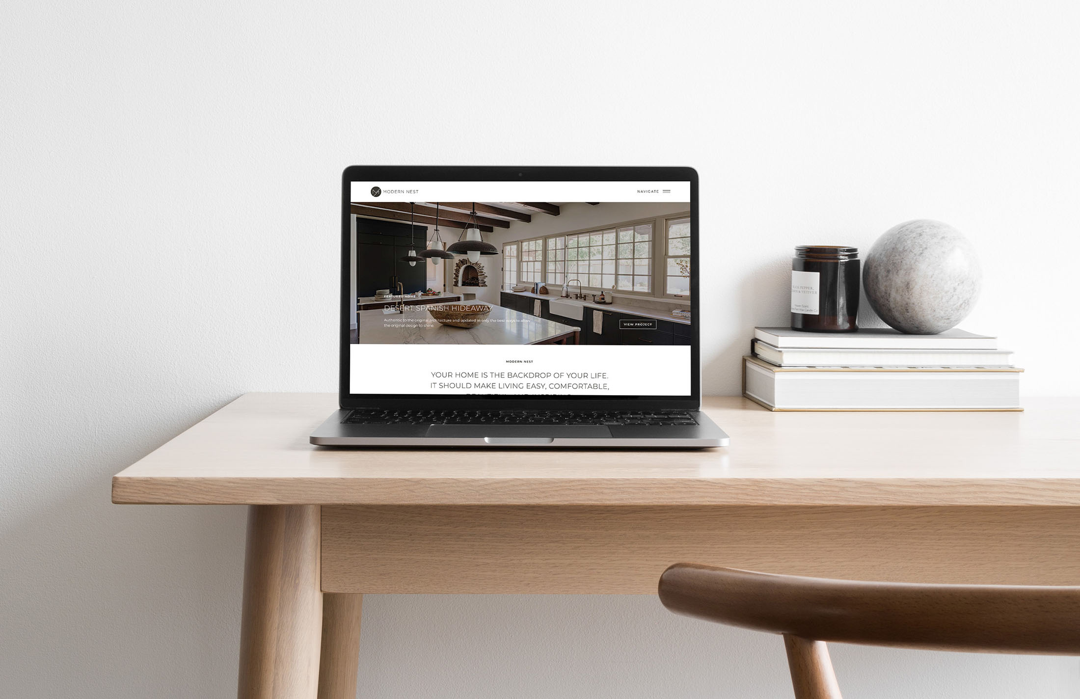 Laptop displaying Modern Nest Homes’ homepage featuring a Desert Spanish Hideaway project on a minimalist wooden desk.