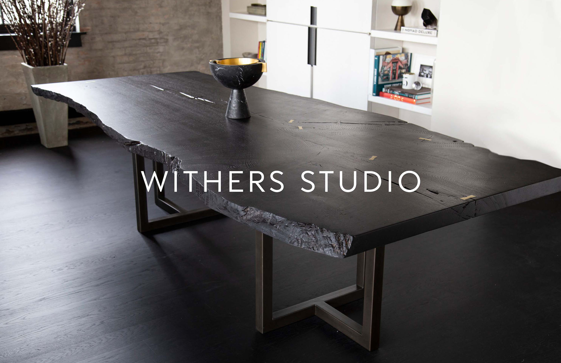 Black live-edge dining table with brass bowtie inlays inspired by Withers Studio’s logo, blending modern craftsmanship with timeless branding in a contemporary interior.