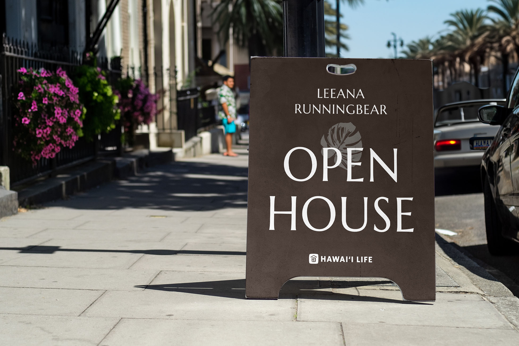 Leeana Runningbear’s open house sign displayed on a sidewalk, featuring her logo, branding, and Hawaii Life association, set against a vibrant street backdrop.