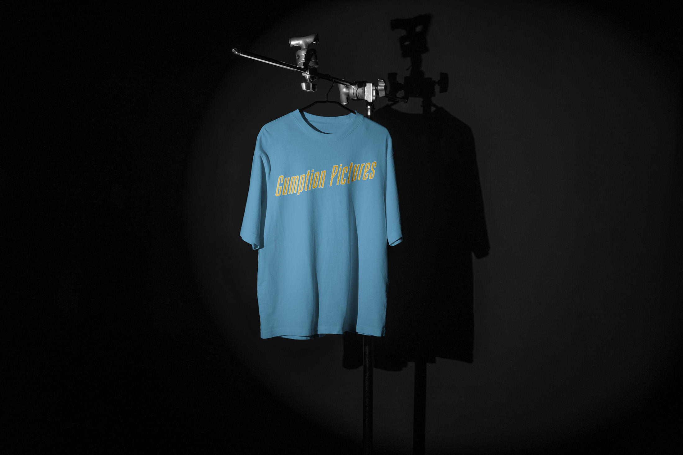 Gumption Pictures branded t-shirt with bold typography and teal accents, demonstrating the brand’s integration into merchandise and apparel.