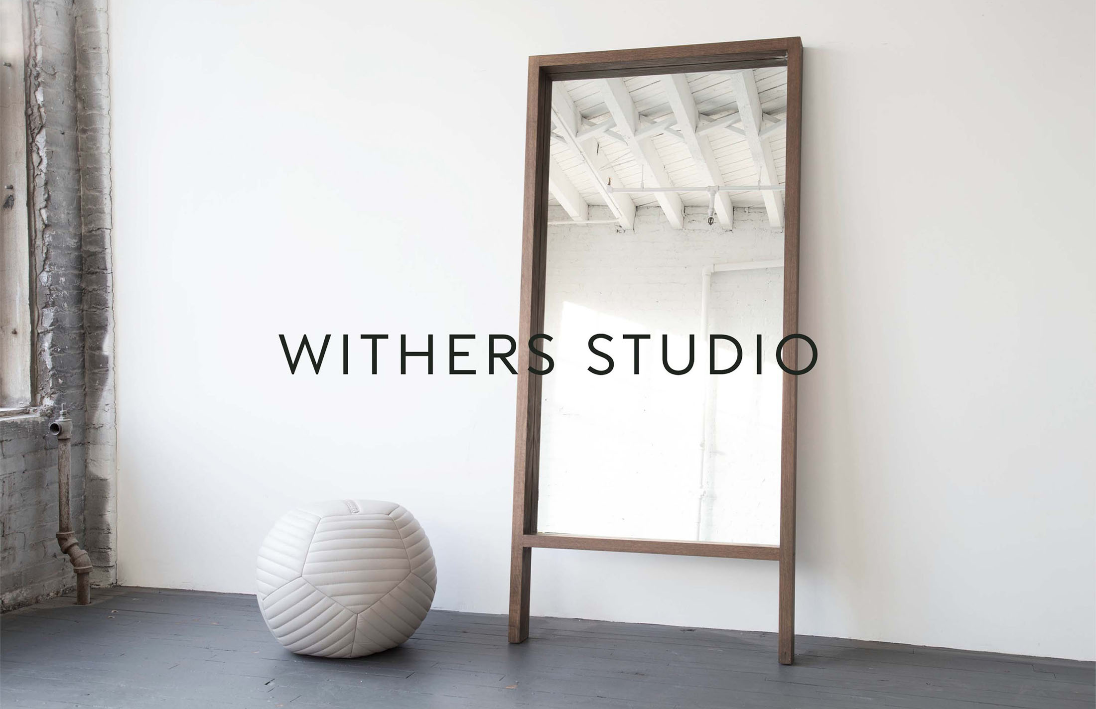 Floor-length mirror with wooden frame in Withers Studio, showcasing minimalist design and branding elements in a clean, modern interior setting.