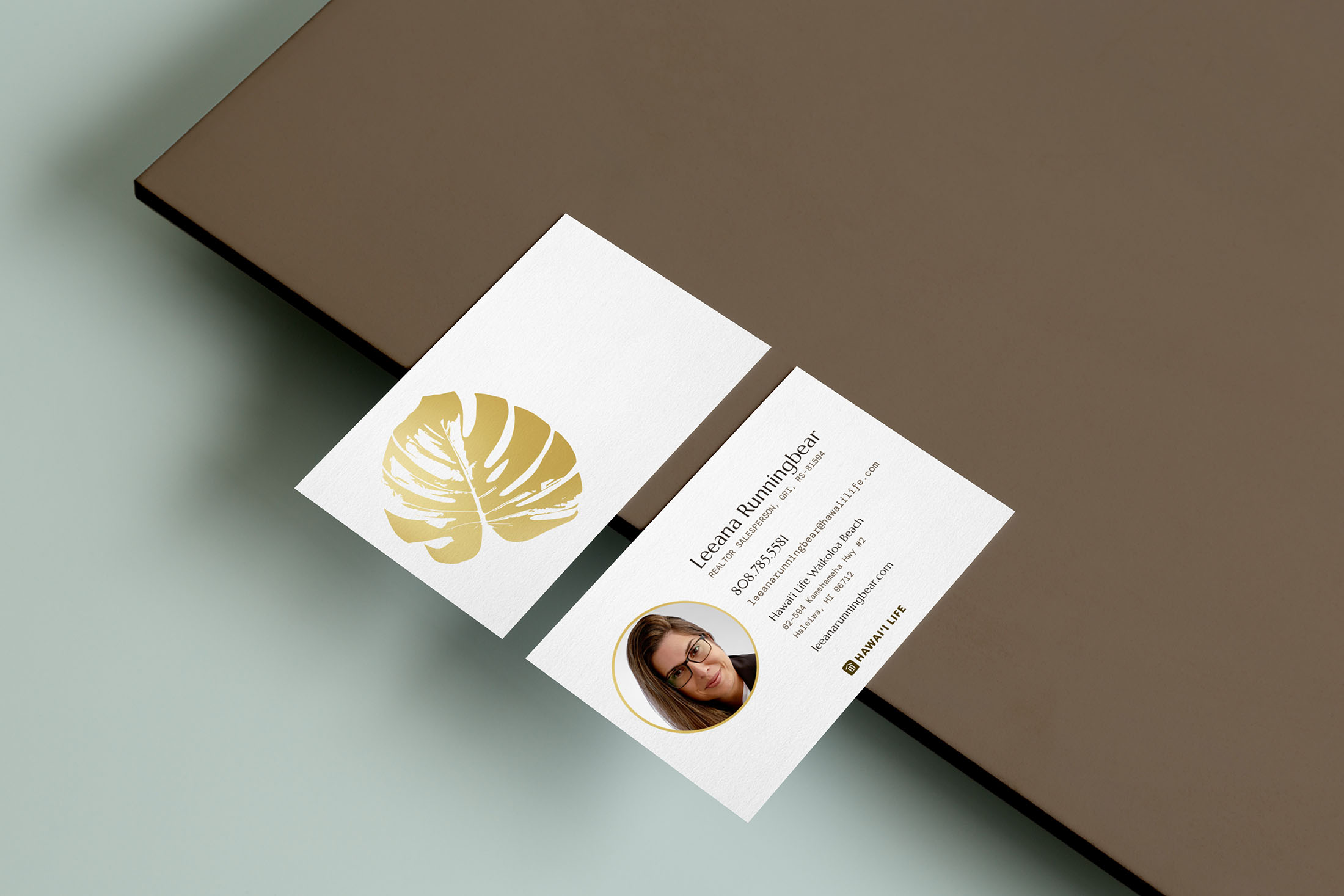 A business card design for Leeana Runningbear Realtor®, featuring the golden Monstera leaf, professional contact details, and a clean, luxurious aesthetic.