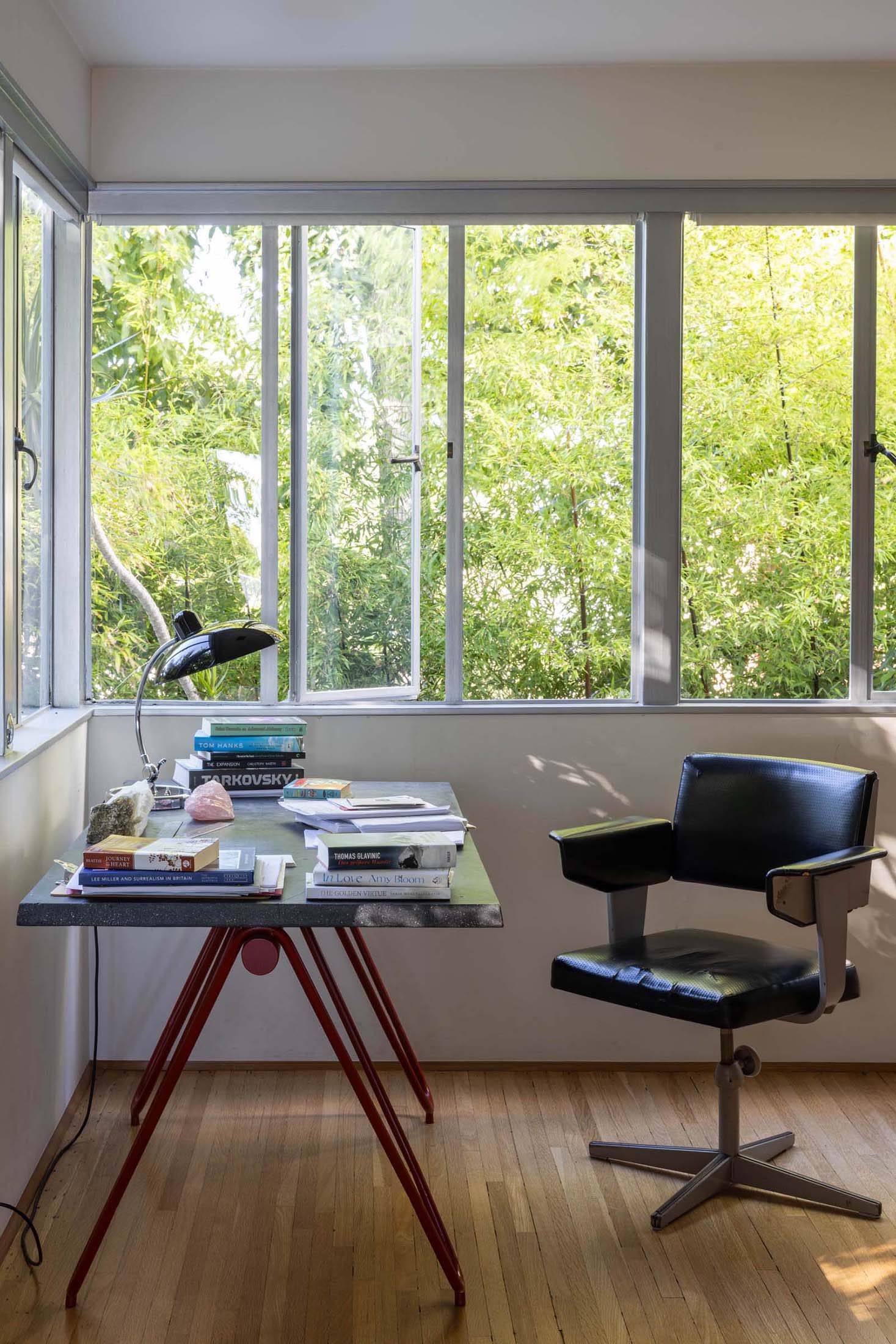 A bright and modern home office with floor-to-ceiling windows showcasing lush greenery outside, creating a serene and inspiring workspace.