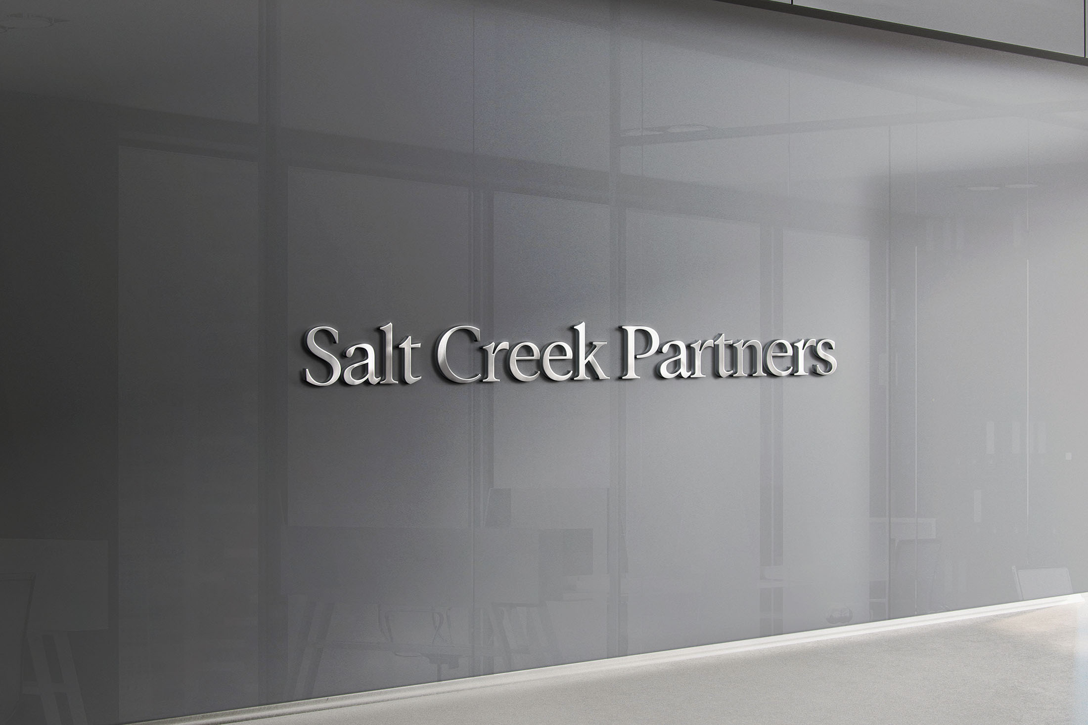 Salt Creek Partners logo displayed in polished silver on a frosted glass wall, symbolizing professionalism and modern sophistication.