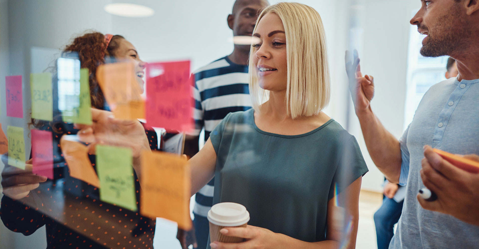 Team collaborating with colorful sticky notes on a glass board, focusing on goal-setting and creative planning for branding and business success.