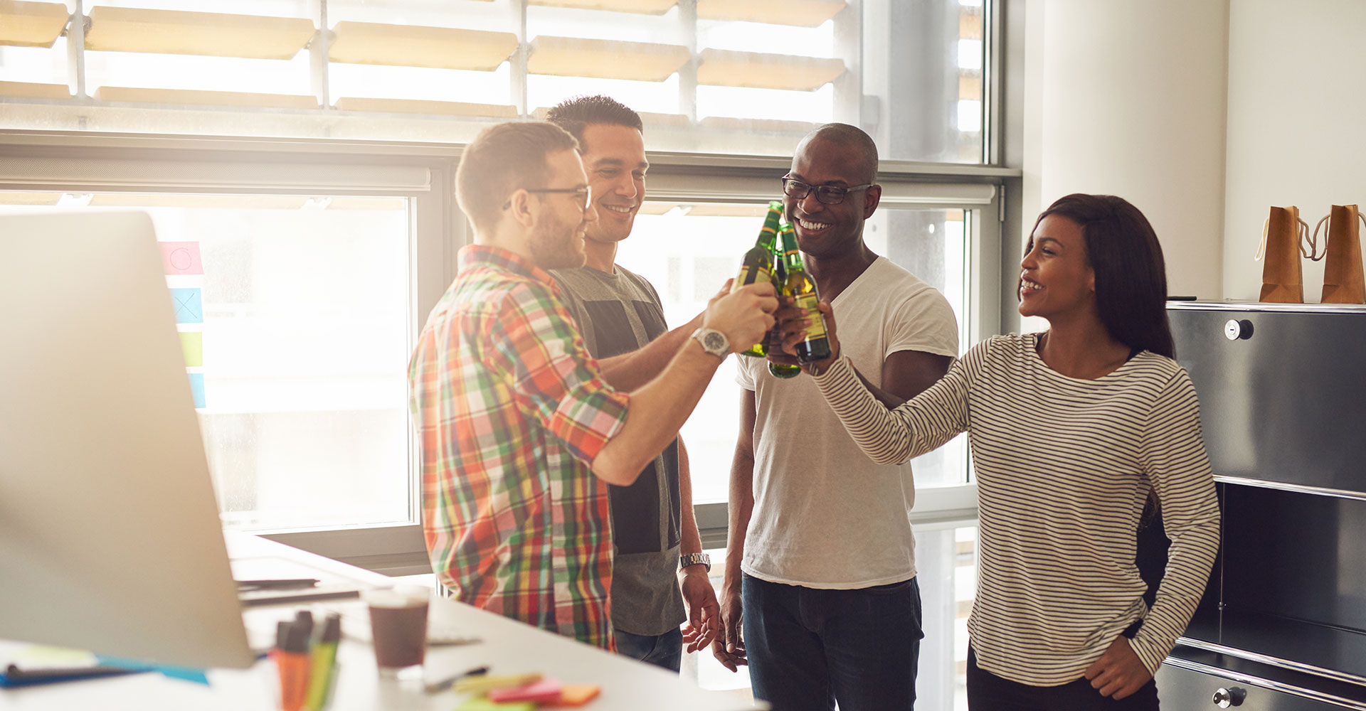 Team celebrating with a toast in a bright office space, symbolizing the importance of work-life balance and winding down the workday effectively.