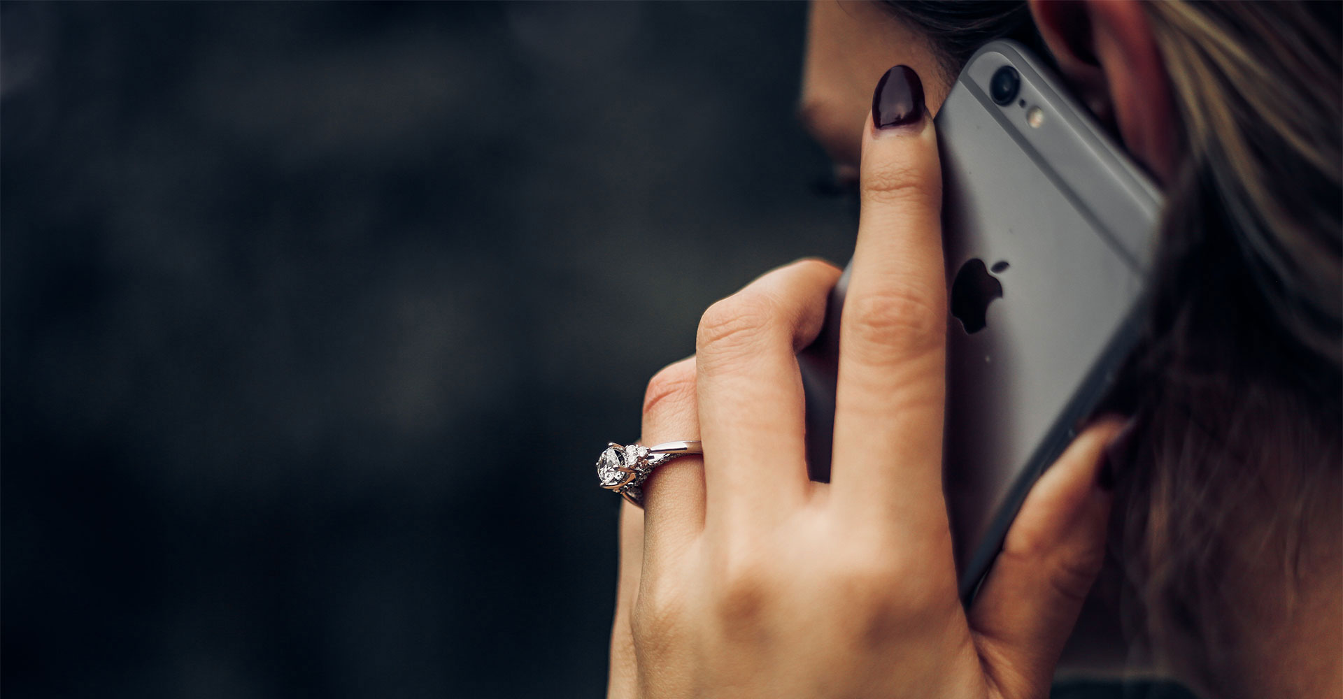 Close-up of a woman holding a phone with a diamond ring visible, representing professional communication and the importance of a well-designed contact page for branding.