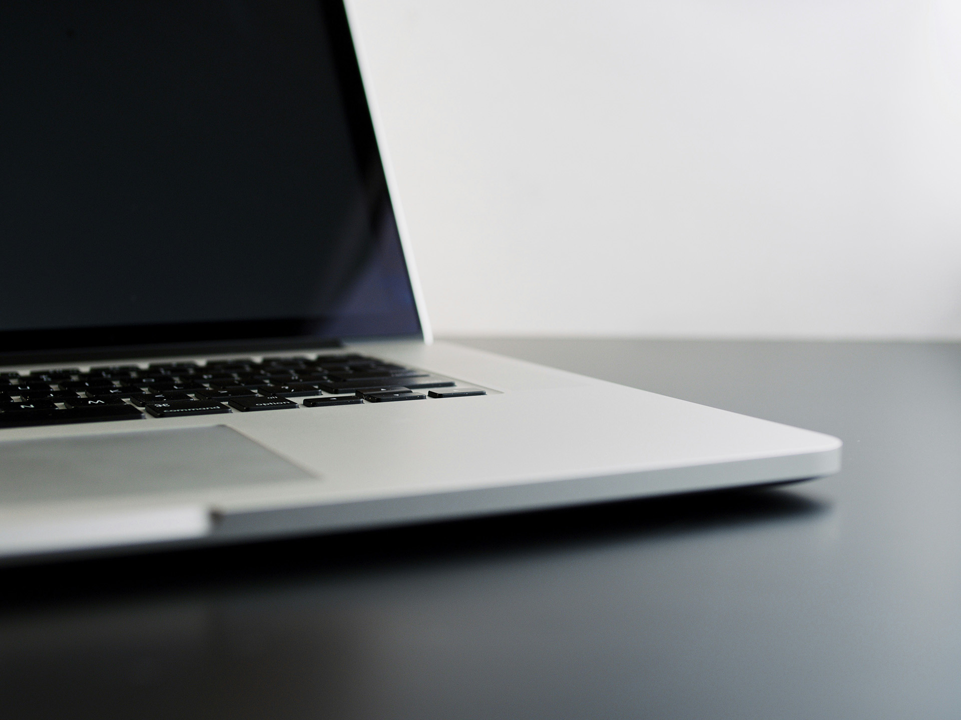 Close-up of a sleek silver laptop on a dark surface, showcasing minimalist design and modern technology.