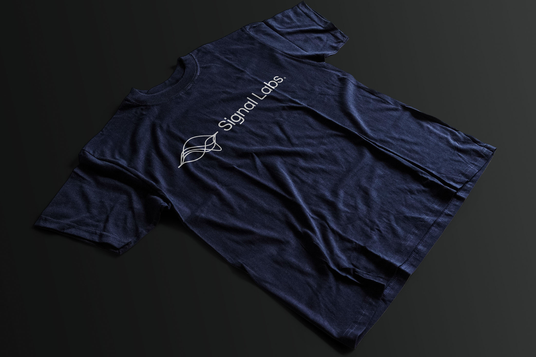 Navy blue Signal Labs t-shirt featuring the logo and brand name printed in white, displayed on a dark background.