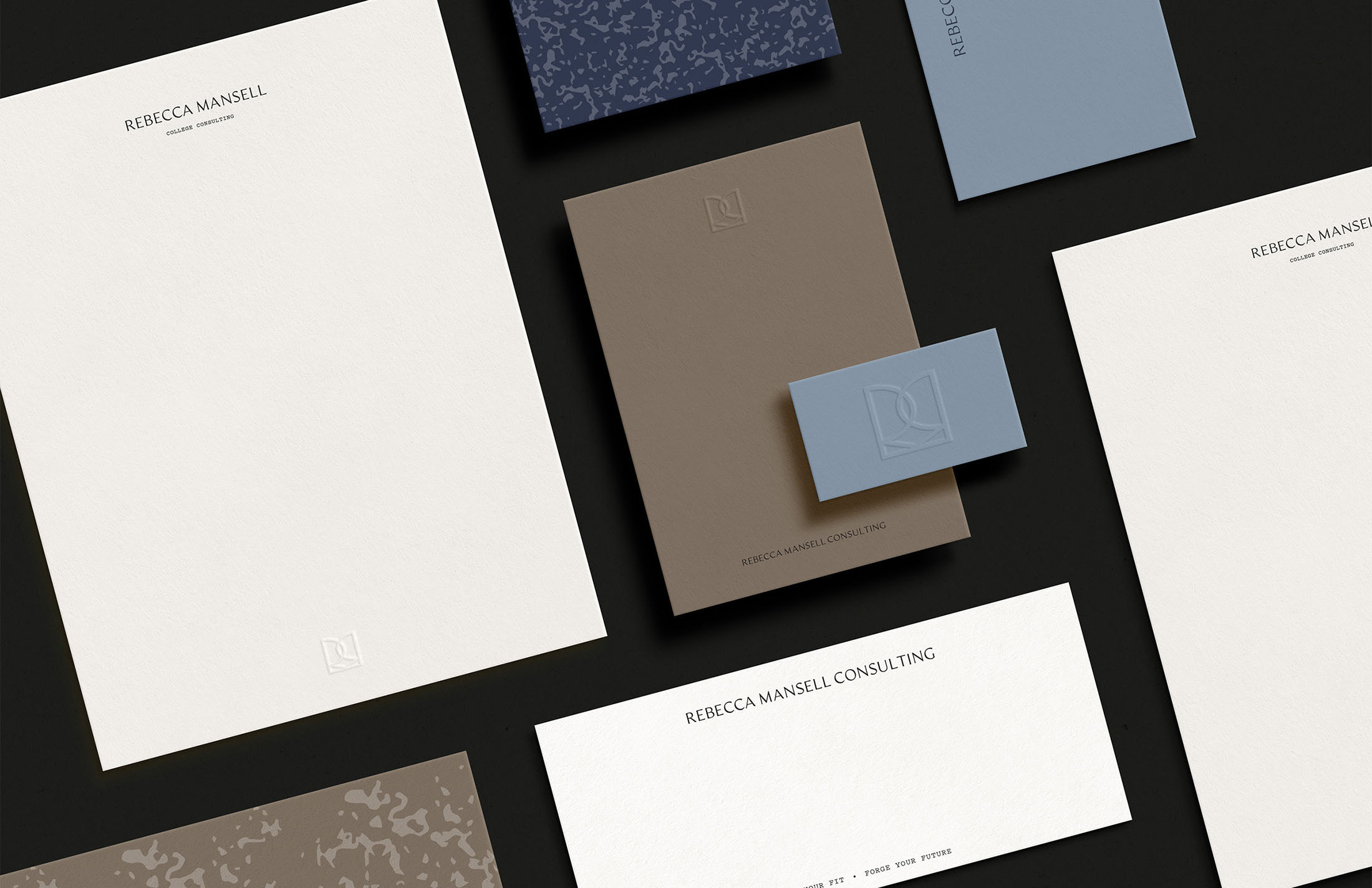 A flat-lay of Rebecca Mansell Consulting stationery featuring business cards, envelopes, and letterhead, showcasing embossed details and a clean, minimalist design.