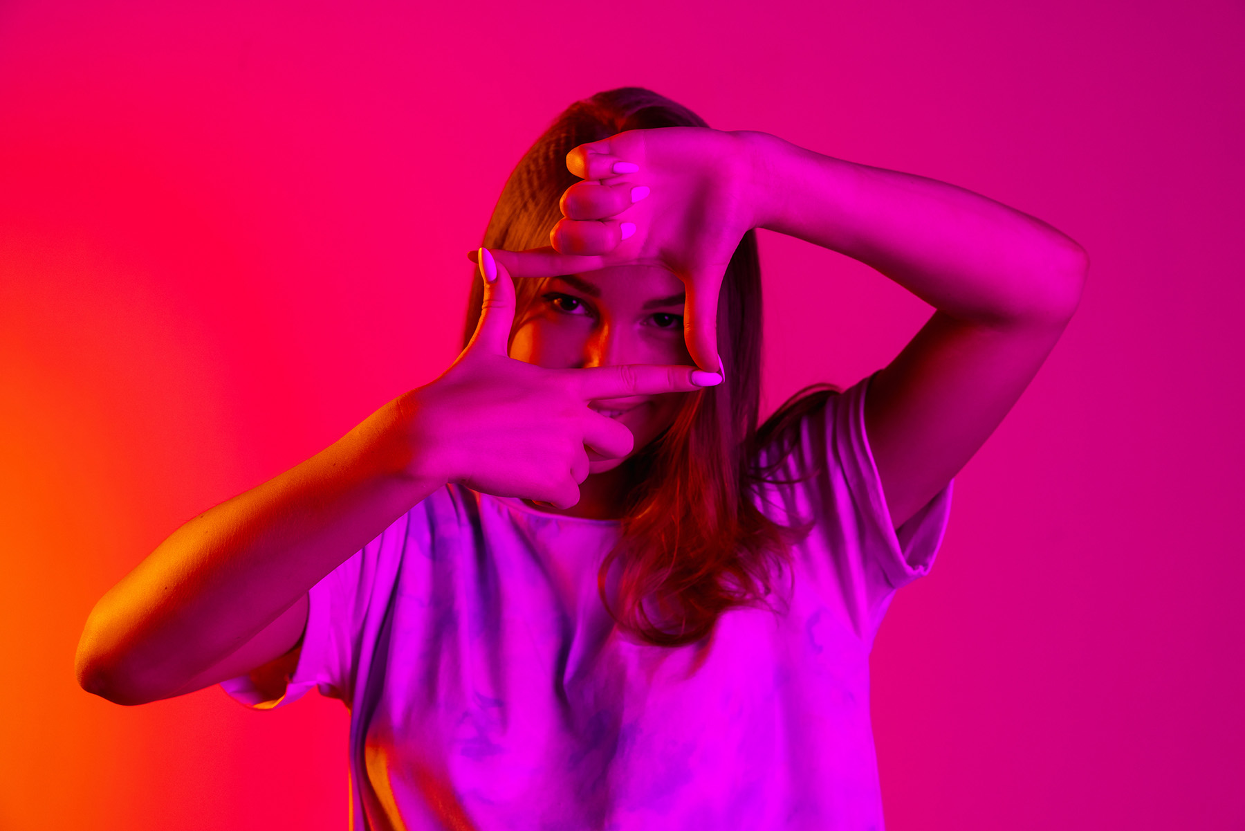 Vibrant portrait of a young woman creating a frame with her hands, symbolizing creativity and visual storytelling, ideal for Instagram branding.