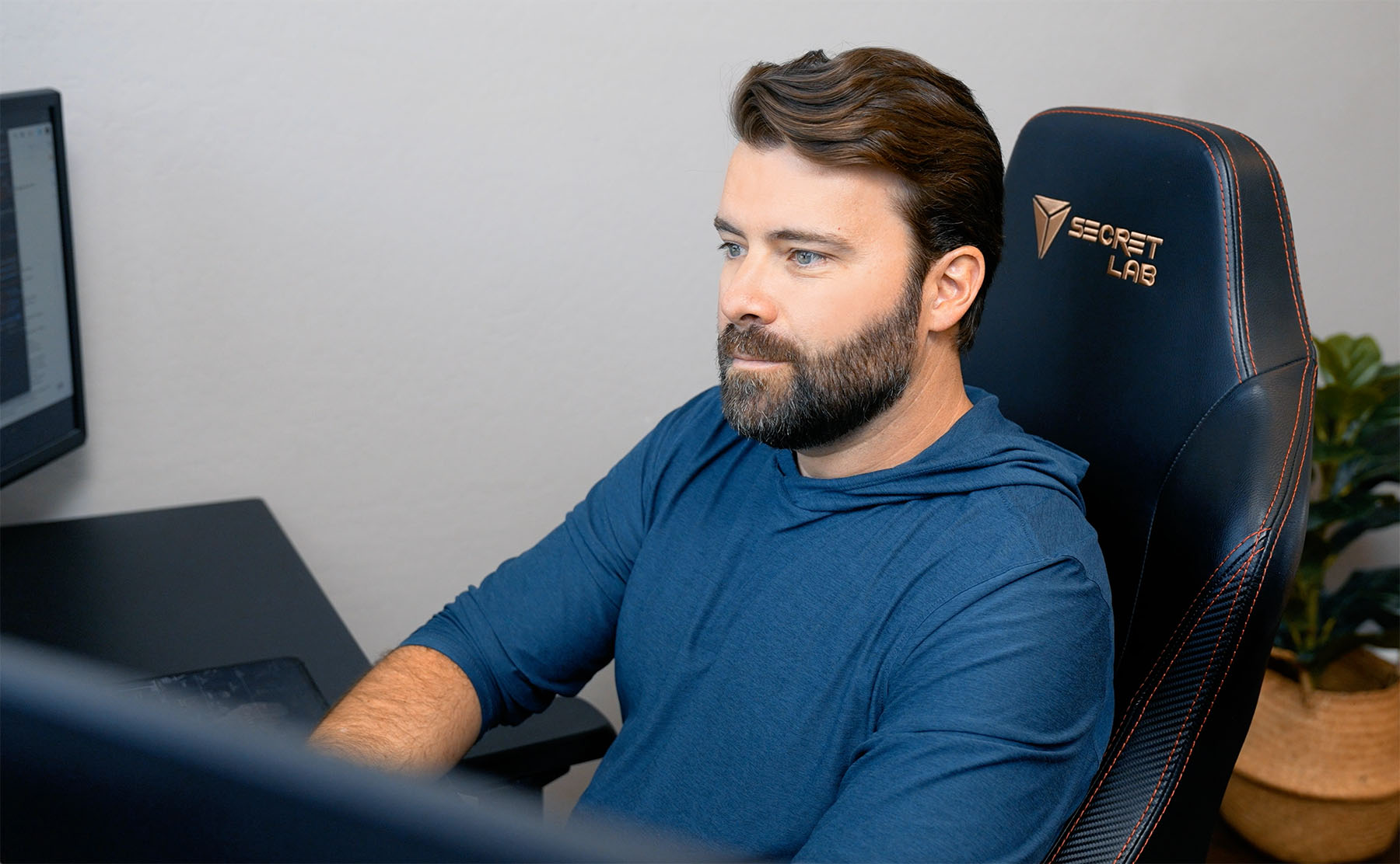 Web designer Steve Harris of Whiskey & Red focused on his work at a computer. He is seated in a professional ergonomic chair in a modern office space, emphasizing expertise in website design and development.