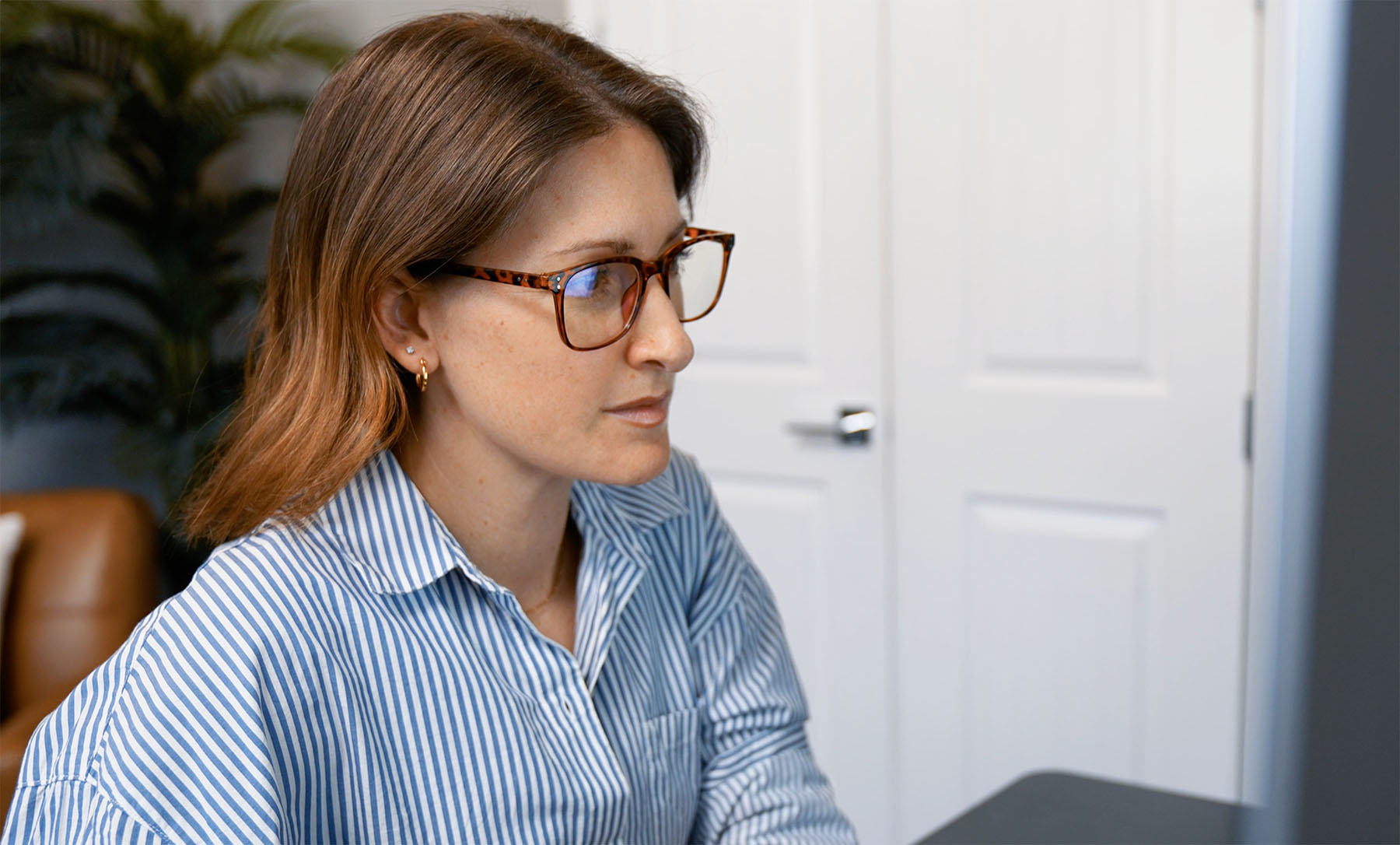 Branding and logo design expert Julie Harris of Whiskey & Red intently working at her desk in a modern office environment. Her focus highlights her expertise in creating impactful brand identities and designs.