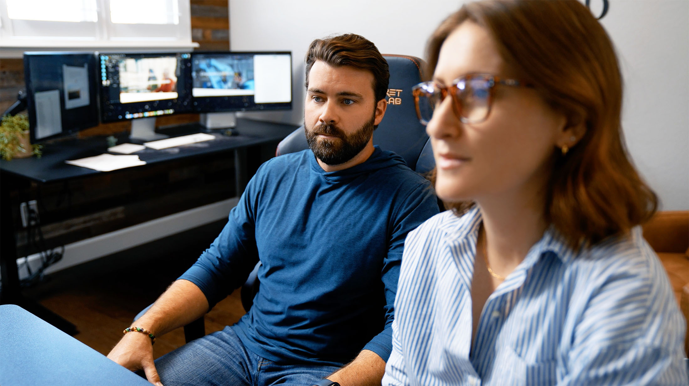 Steve Harris and Julie Harris of Whiskey & Red in a client meeting, focused on branding and web design strategies, in a modern office with dual monitors displaying creative work.