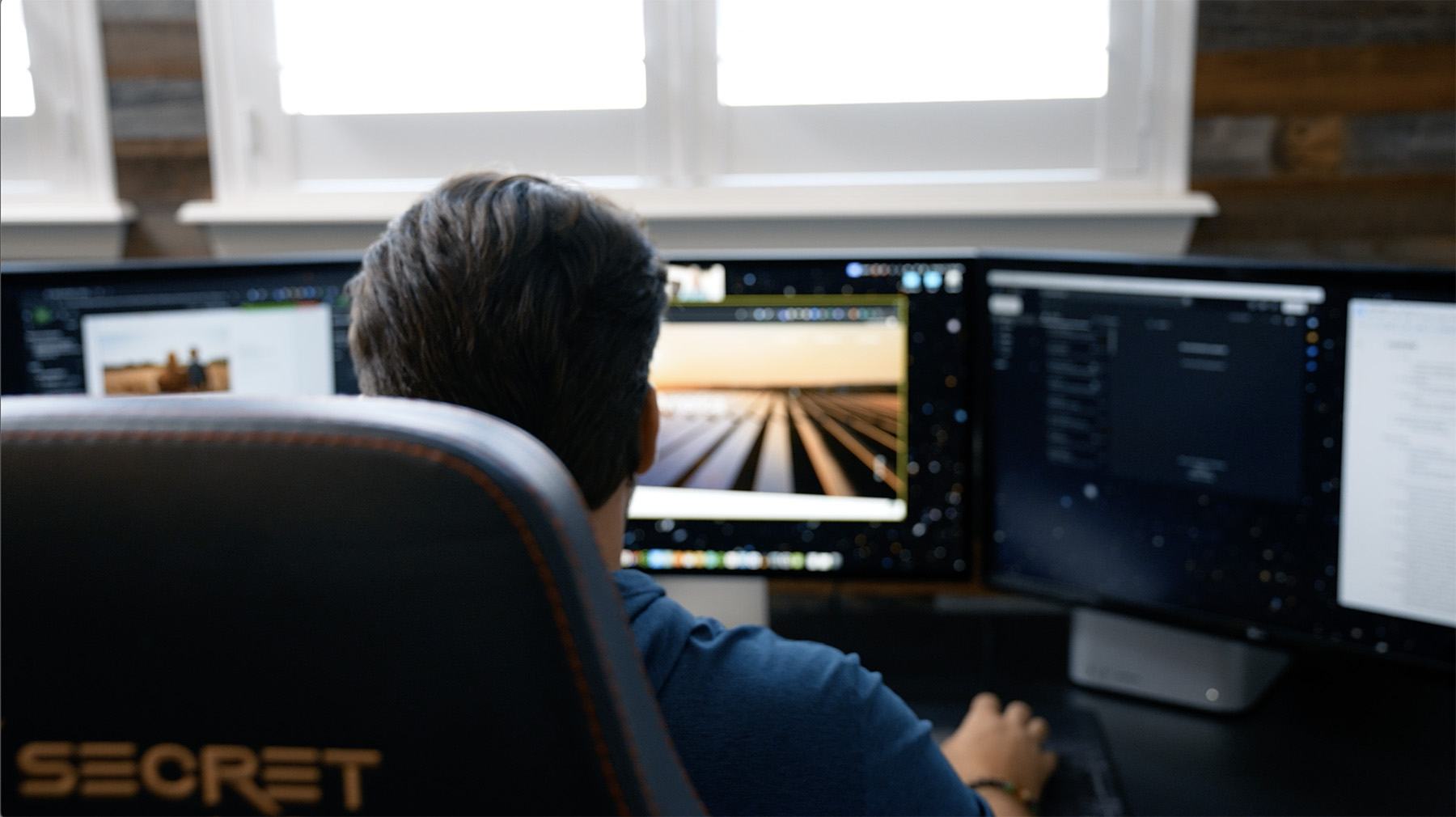 Web designer Steve Harris of Whiskey & Red working at a multi-monitor setup, creating a visually stunning website design. The workspace reflects a high level of creativity and technical precision.