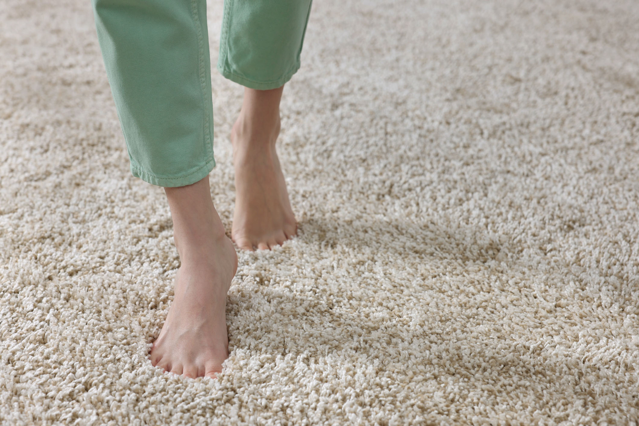 Close-up of bare feet walking on freshly cleaned, plush beige carpet, illustrating softness and cleanliness ideal for toxin-free, family-safe home environments.