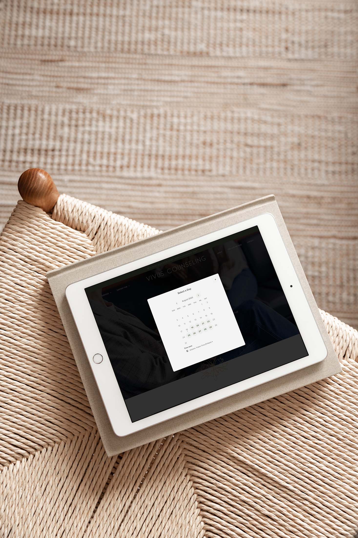 Vivus Counseling appointment booking calendar displayed on a tablet resting on a woven chair, representing user-friendly digital therapy access.