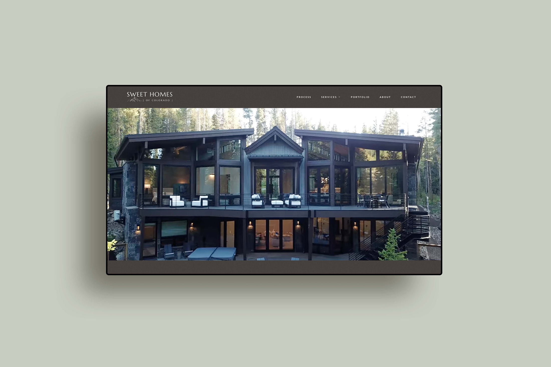 Modern custom mountain home exterior with expansive windows surrounded by forested landscape