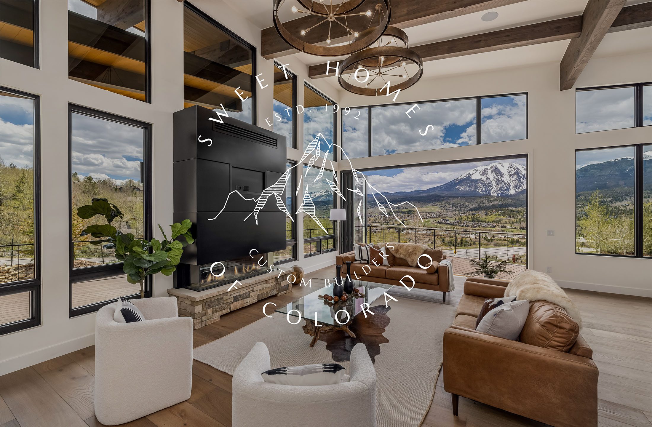Bright, modern living room with vaulted ceilings, floor-to-ceiling windows, mountain views, and Sweet Homes of Colorado branding.